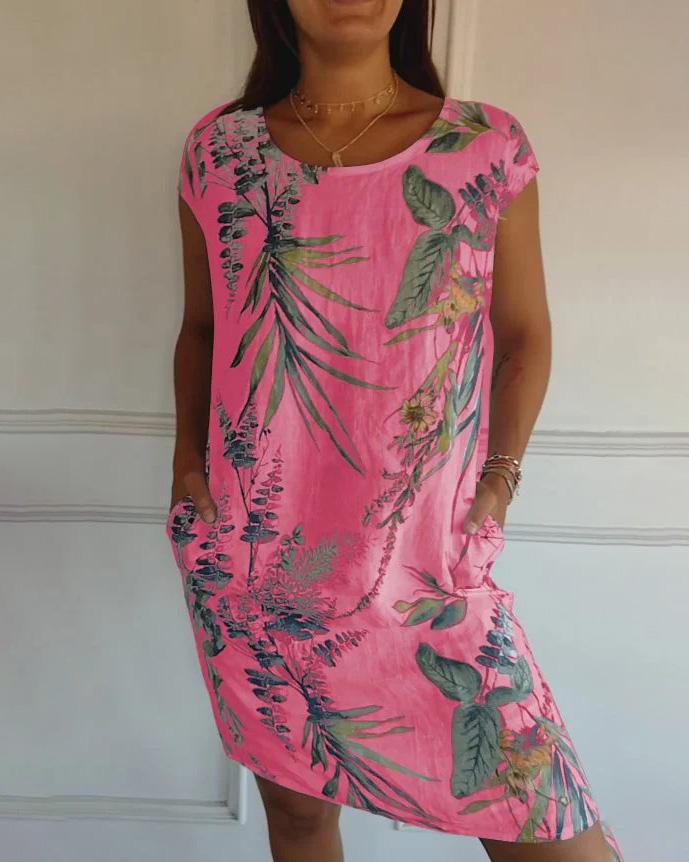 Frau in pinkem Sommerkleid mit tropischem Blumenmuster, lässig geschnitten, knielang, mit kurzen Ärmeln, vor weißem Hintergrund.