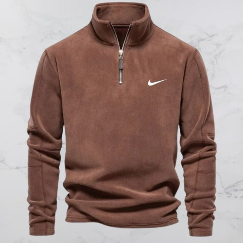 Brauner Nike Pullover mit Reißverschluss, aus Fleece, auf Marmorhintergrund. Sportbekleidung, Herrenmode, Nike Logo sichtbar.