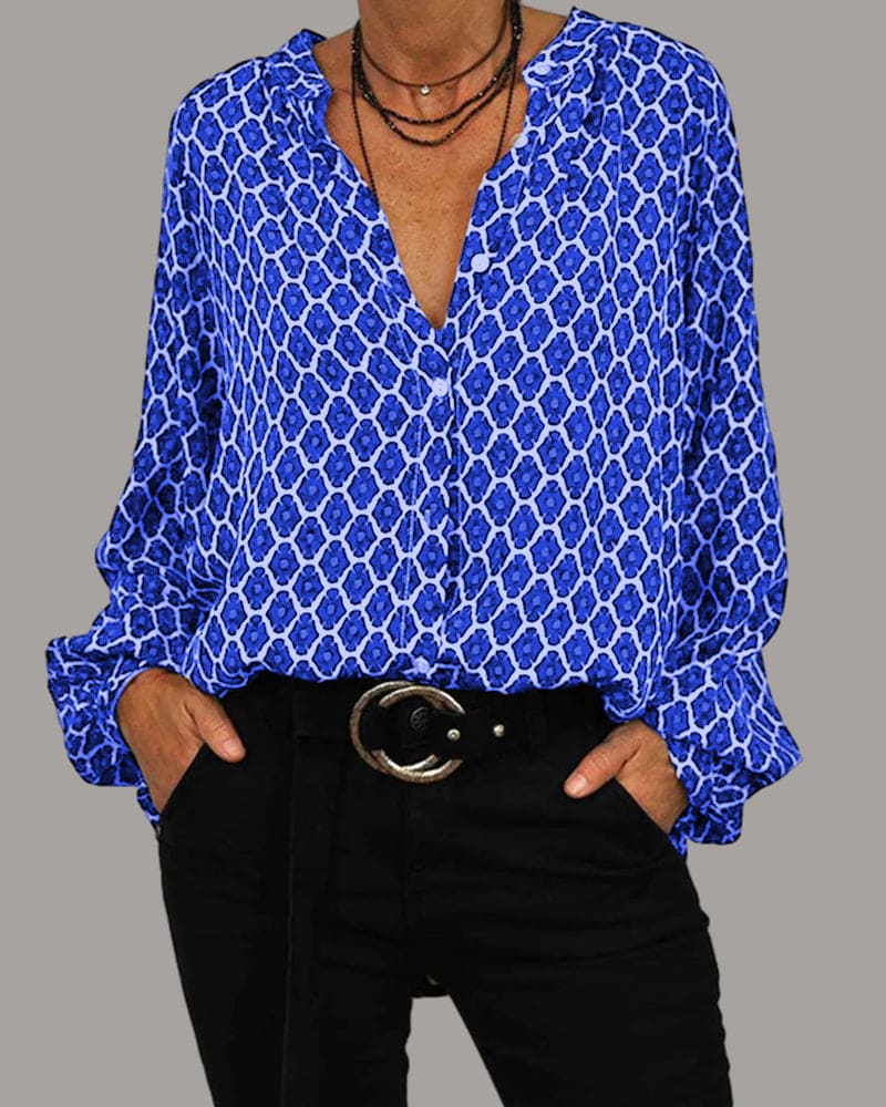 Frau in blauer gemusterter Bluse mit V-Ausschnitt und schwarzer Hose. Modetrend, Damenmode, stilvolle Freizeitkleidung.