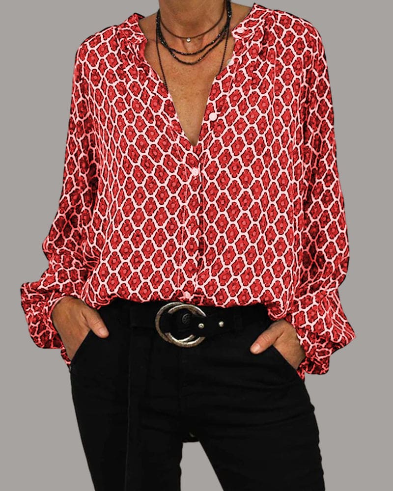 Rote Damenbluse mit geometrischem Muster, V-Ausschnitt und langen Ärmeln, kombiniert mit schwarzer Hose und Gürtel. Modetrend, stilvolle Damenbekleidung.