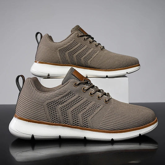 Graue Herren-Sneaker mit weißer Sohle, atmungsaktivem Mesh-Obermaterial und Schnürsenkeln. Modische Freizeitschuhe für Alltag und Sport.