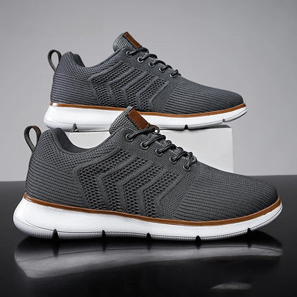 Graue Herren-Sneaker mit weißer Sohle, atmungsaktivem Mesh-Obermaterial und braunen Akzenten, ideal für Sport und Freizeit.