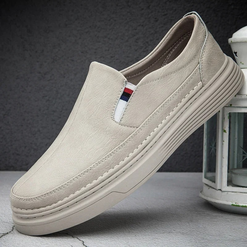 Beiger Herren-Slipper aus Leder mit gestreiftem Detail, rutschfester Sohle und modernem Design. Perfekt für Freizeit und Alltag.