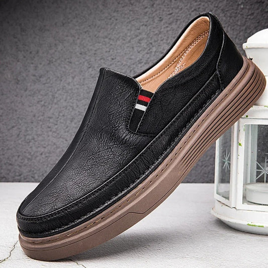 Schwarzer Herren-Slipper aus Leder mit brauner Sohle, modernem Design und rotem Streifen, ideal für Freizeit und Business. Bequeme Herrenschuhe.