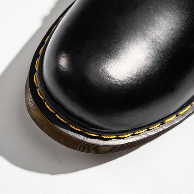 Schwarzer Lederschuh mit gelber Naht, Nahaufnahme. Hochwertige, glänzende Oberfläche, robuste Sohle. Modischer, langlebiger Schuh.