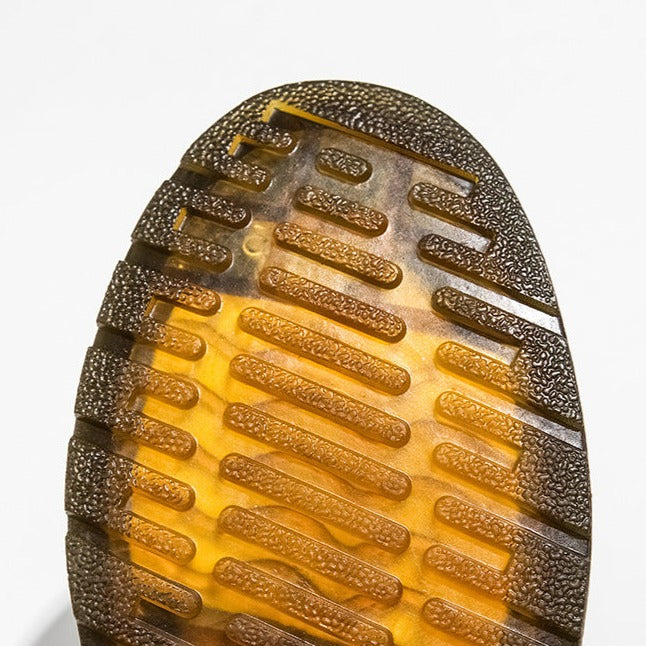 Nahaufnahme einer strukturierten, braun-gelben Schuhsohle mit rutschfestem Profil. Ideal für Outdoor-Aktivitäten und modische Sneaker.