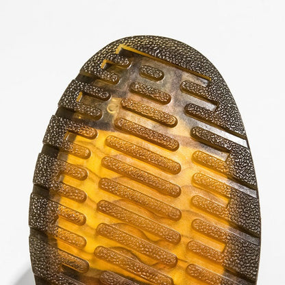 Nahaufnahme einer strukturierten, braun-gelben Schuhsohle mit rutschfestem Profil. Ideal für Outdoor-Aktivitäten und modische Sneaker.