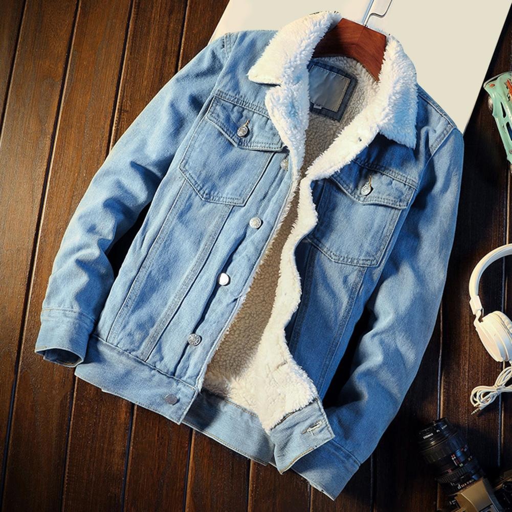 Blaue Jeansjacke mit weißem Futter auf Holzboden, neben Kopfhörern und Kamera. Modische Herrenjacke, ideal für Herbst und Winter.