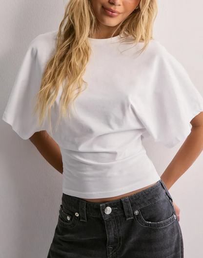 Blonde Frau in weißem T-Shirt mit weiten Ärmeln und schwarzer Jeans vor weißem Hintergrund. Modetrend, lässiger Look, Damenbekleidung.