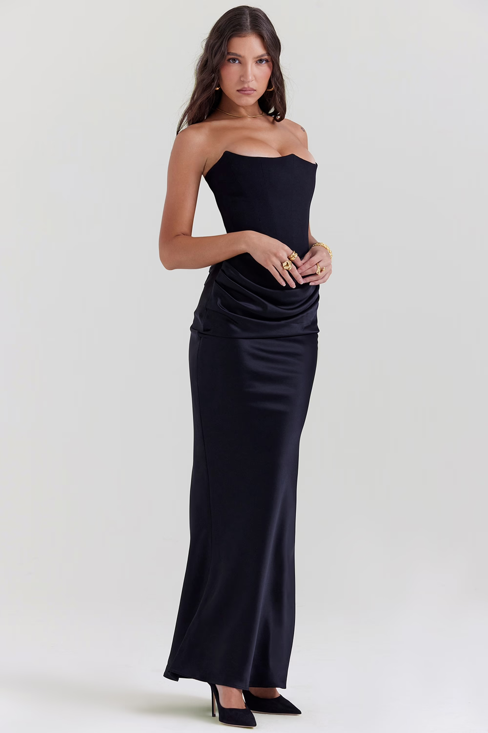 Frau in elegantem, schwarzem, schulterfreiem Abendkleid, posiert vor neutralem Hintergrund. Perfekt für formelle Anlässe und Modeevents.