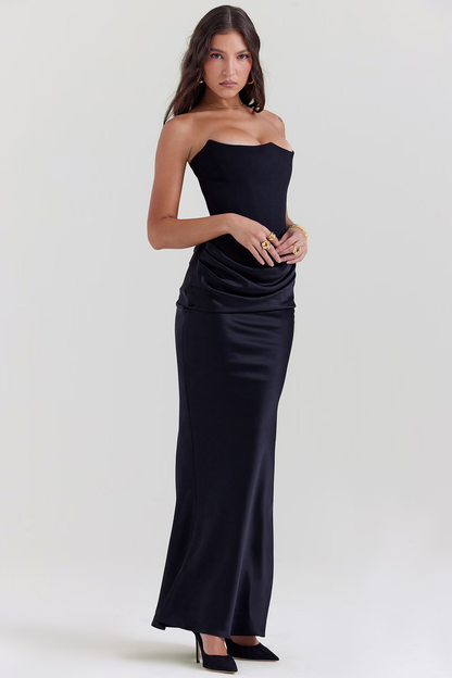 Frau in elegantem, schwarzem, schulterfreiem Abendkleid, posiert vor neutralem Hintergrund. Perfekt für formelle Anlässe und Modeevents.