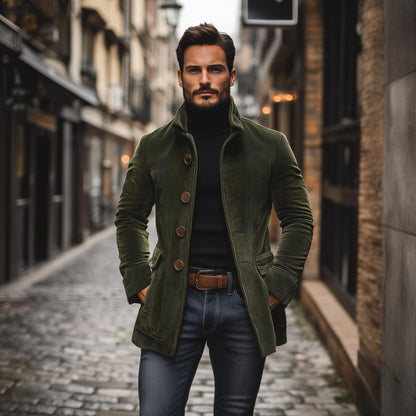 Mann in grünem Mantel und schwarzem Rollkragenpullover auf gepflasterter Straße. Modischer Herbstlook, urbane Kulisse, stilvolle Herrenmode.