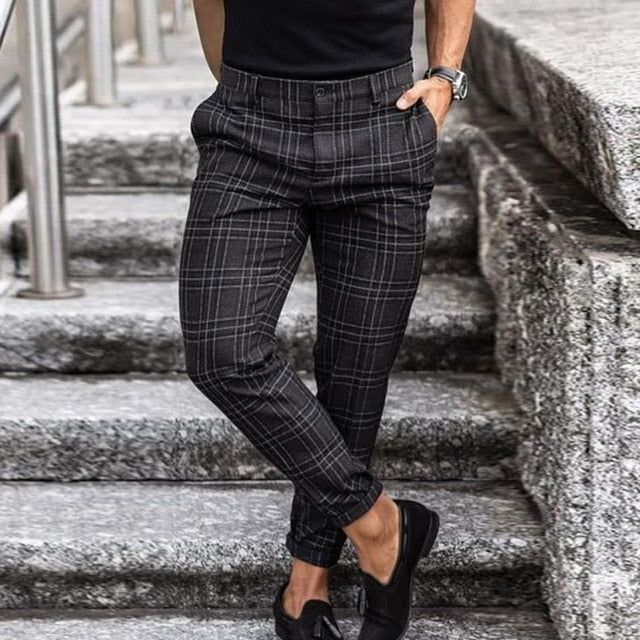 Mann in karierter Anzughose und schwarzen Slippern auf Treppe. Elegante Herrenmode, stilvolle Business-Kleidung, modische Herrenhose.