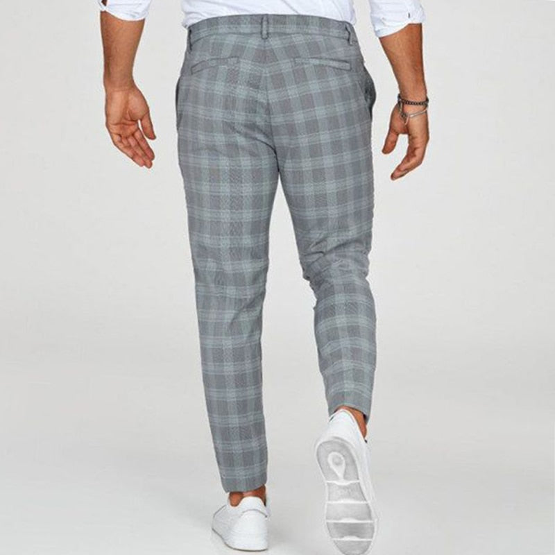 Mann in grauer karierter Hose und weißen Sneakers von hinten. Modetrend, Herrenbekleidung, stilvolle Freizeitmode.