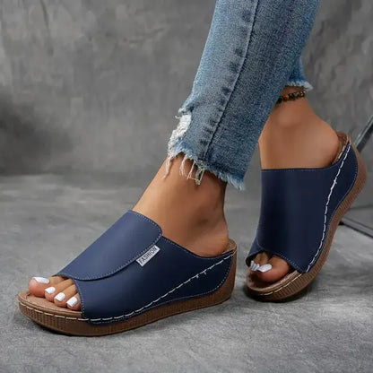 Damen Sandalen mit Keilabsatz, blauem Obermaterial und offener Zehenpartie, kombiniert mit zerrissenen Jeans. Bequeme Sommerschuhe für Frauen.
