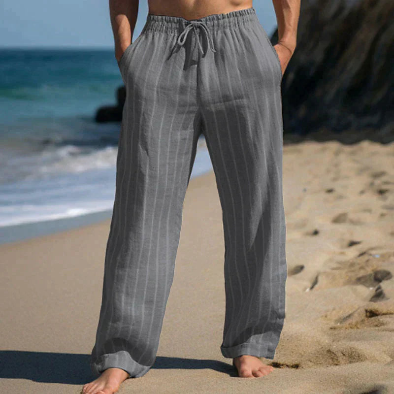 Graue Leinenhose am Strand, lässig und bequem, ideal für Sommermode. Perfekt für Strandspaziergänge und entspannte Freizeitkleidung.