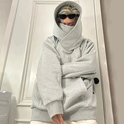 Grauer Oversize-Hoodie, Person mit Sonnenbrille, Kapuze hochgezogen, modischer Streetwear-Look, urbaner Stil, lässige Kleidung.