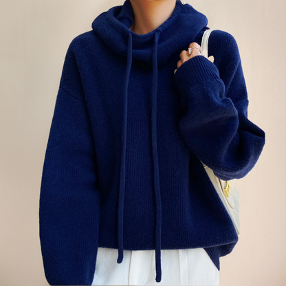 Dunkelblauer Strickpullover mit Kapuze und Kordeln, getragen von Person. Modischer, bequemer Winterpullover für Damen. Ideal für kalte Tage.