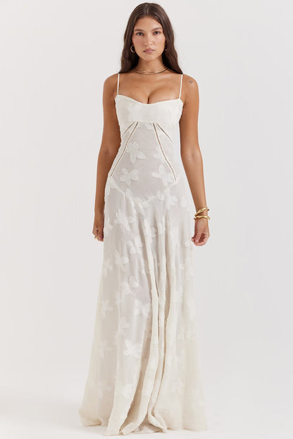 Frau in elegantem, langem, weißem Kleid mit Blumenmuster und Spaghettiträgern. Perfekt für Sommermode, Abendveranstaltungen, Hochzeiten.