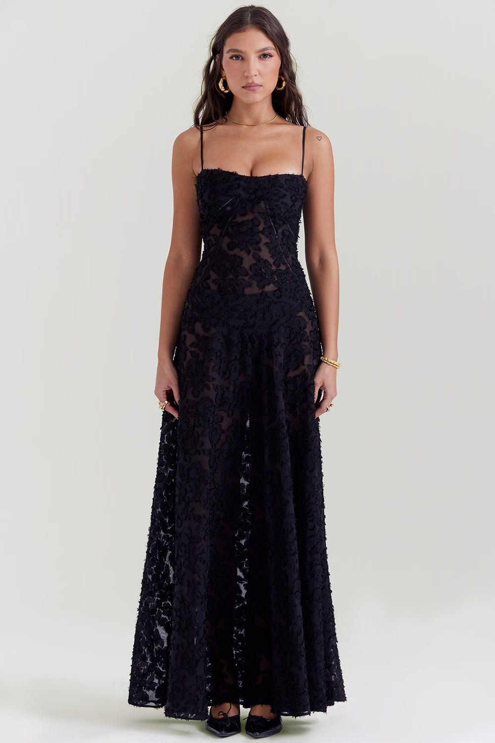 Frau in elegantem, schwarzem Spitzenkleid mit Spaghettiträgern, bodenlang. Perfekt für Abendmode, formelle Anlässe, stilvolle Damenmode.