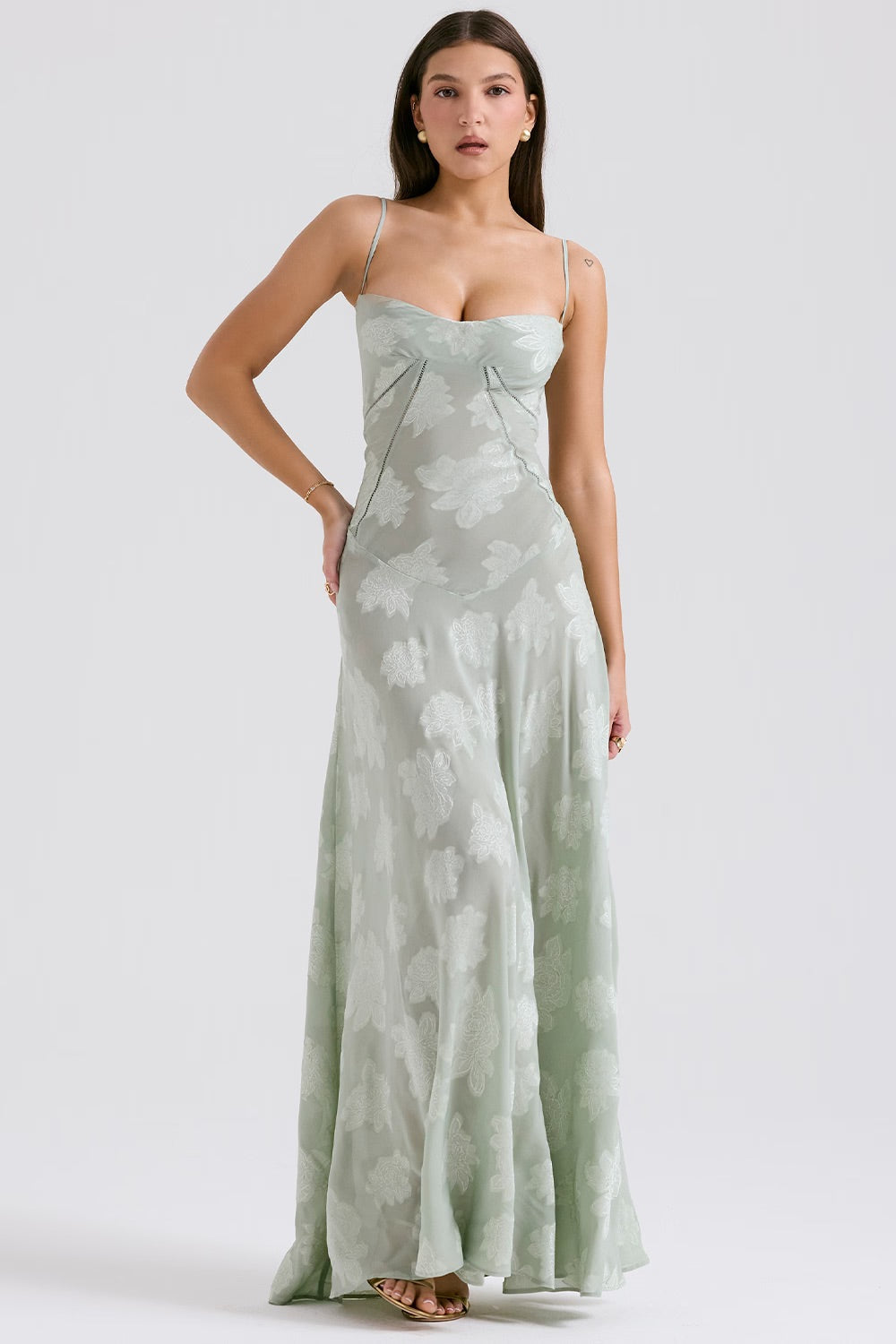 Frau in langem, hellgrünem Abendkleid mit Blumenmuster, Spaghettiträgern und herzförmigem Ausschnitt. Elegante Mode, Abendgarderobe, Damenkleidung.