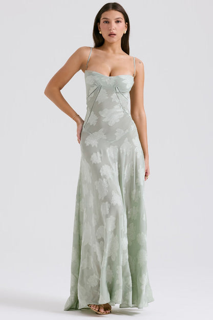 Frau in langem, hellgrünem Abendkleid mit Blumenmuster, Spaghettiträgern und herzförmigem Ausschnitt. Elegante Mode, Abendgarderobe, Damenkleidung.