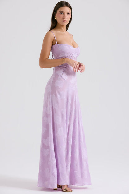 Frau in einem eleganten, fliederfarbenen Abendkleid mit Spaghettiträgern, stehend vor weißem Hintergrund. Mode, Abendkleid, Damenbekleidung.