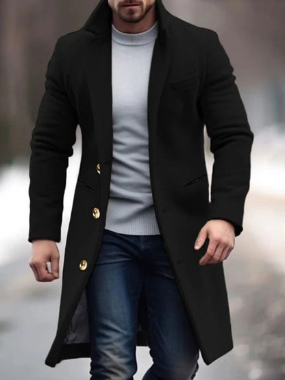 Mann in schwarzem Wollmantel mit goldenen Knöpfen, weißem Pullover und blauer Jeans spaziert im Winter. Elegante Herrenmode, Wintermantel.