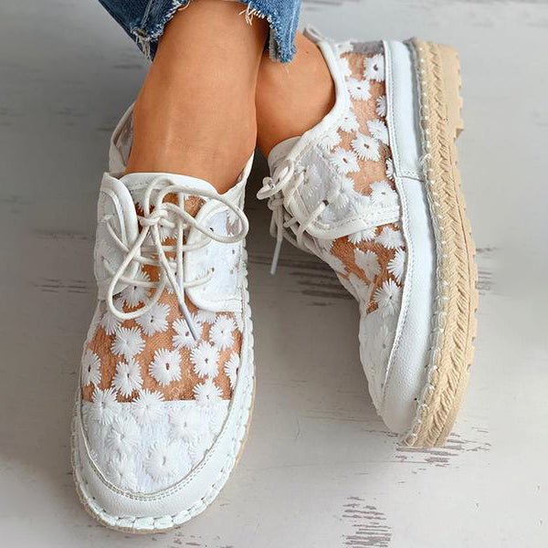 Weiße Damen-Sneaker mit Blumenmuster, Spitzen-Details und Bastsohle. Modische Sommerschuhe, ideal für Freizeit und Alltag.