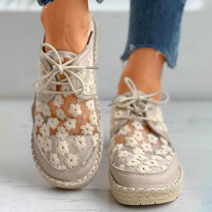 Damen-Sneaker mit Blumenmuster, beige, aus Spitze und Leder, Espadrille-Stil, getragen mit blauen Jeans. Modische Frühlingsschuhe.
