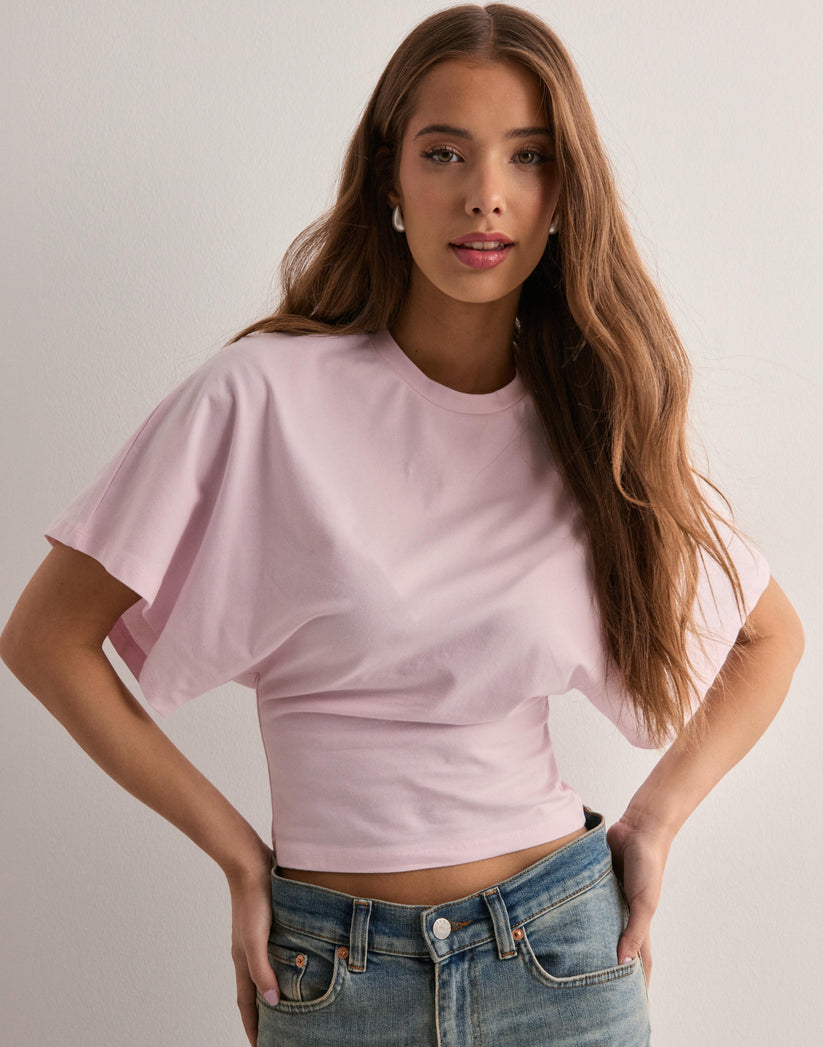 Junge Frau in rosa T-Shirt und blauer Jeans vor weißem Hintergrund. Mode, lässiger Stil, Damenbekleidung, trendige Outfits.