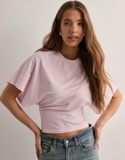 Junge Frau in rosa T-Shirt und blauer Jeans vor weißem Hintergrund. Mode, lässiger Stil, Damenbekleidung, trendige Outfits.