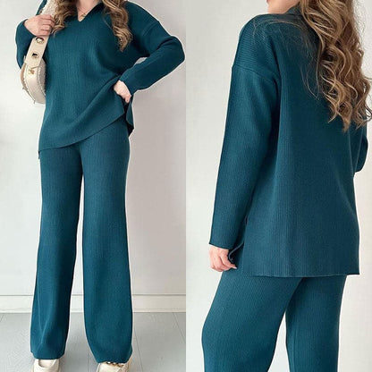 Frau in dunkelgrünem Strick-Set mit Pullover und Hose, beige Tasche, weiße Sneaker. Modetrend, bequeme Damenbekleidung, eleganter Freizeitlook.