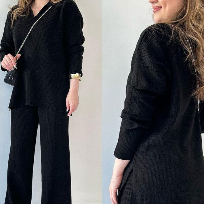 Frau in schwarzem Strickanzug mit V-Ausschnitt und weiten Hosen, trägt kleine schwarze Umhängetasche, modisches Outfit, eleganter Look.