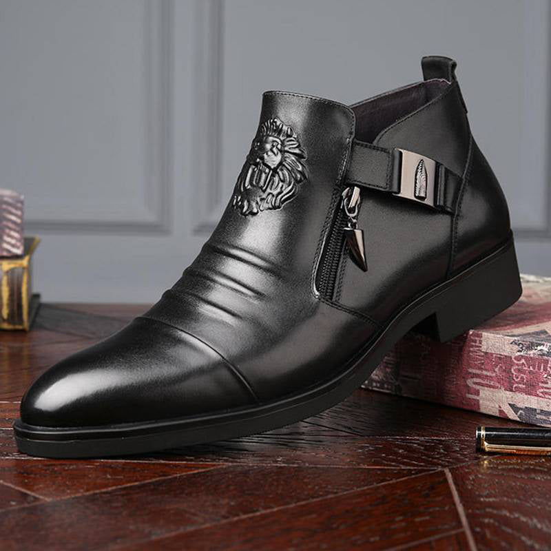 Schwarzer Herren-Lederstiefel mit Löwenemblem, seitlichem Reißverschluss und Schnalle auf Holzboden. Eleganter, modischer Ankle Boot.