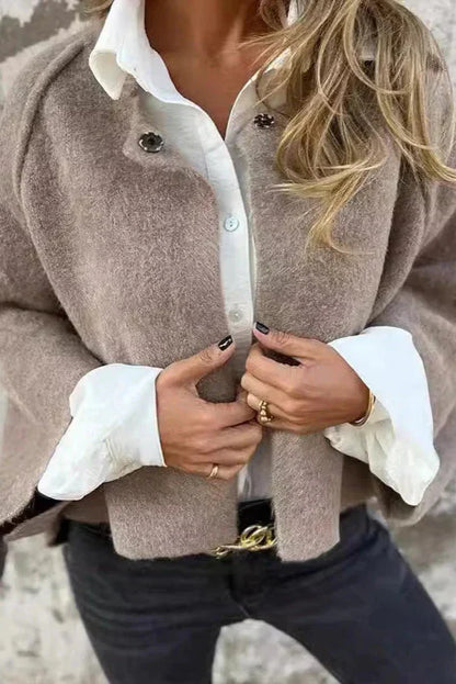 Frau in eleganter Herbstmode: Beigefarbener Wollmantel, weißes Hemd, schwarze Jeans. Stilvolle Kleidung, Mode, Damenbekleidung, Herbsttrends.