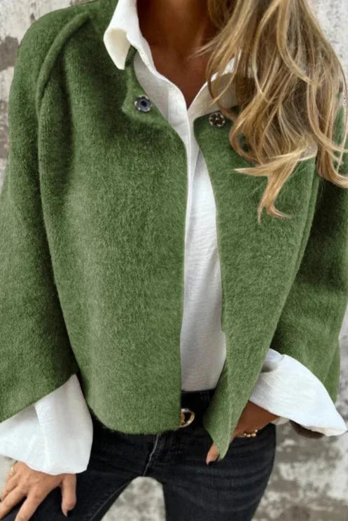 Grüne Damenjacke aus Wolle, kombiniert mit weißer Bluse und schwarzer Jeans. Modetrend Herbst, stilvolle Damenbekleidung, elegantes Outfit.