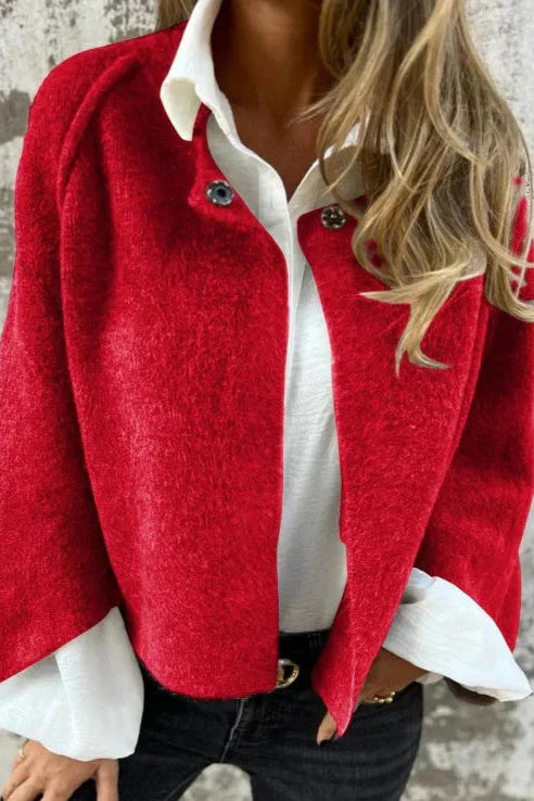 Frau in roter Jacke und weißer Bluse, modisch gekleidet, vor grauer Wand. Trendige Damenmode, Herbstoutfit, stilvolle Kleidung.