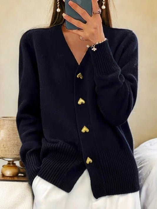 Frau in schwarzem Cardigan mit Herzknöpfen, hält Smartphone. Elegante Mode, Herbstoutfit, Strickjacke Damen, stilvoller Look.
