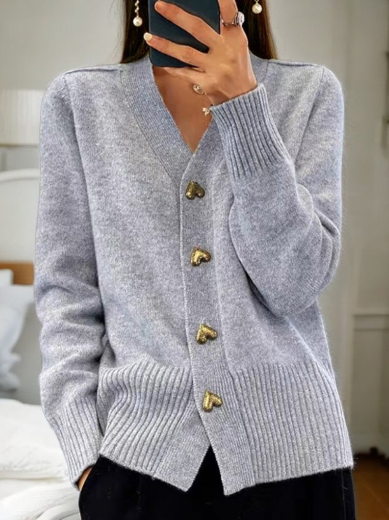 Frau trägt graue Strickjacke mit Herzknöpfen, modisch und elegant, ideal für Herbstmode. Perfekt für stilvolle, gemütliche Outfits.