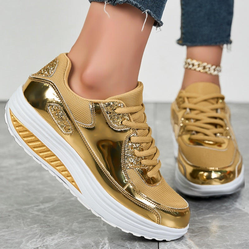 Goldene Sneaker mit glänzenden Details und weißer Sohle, getragen von einer Person in Jeans. Modische Damenschuhe, trendige Sportschuhe.