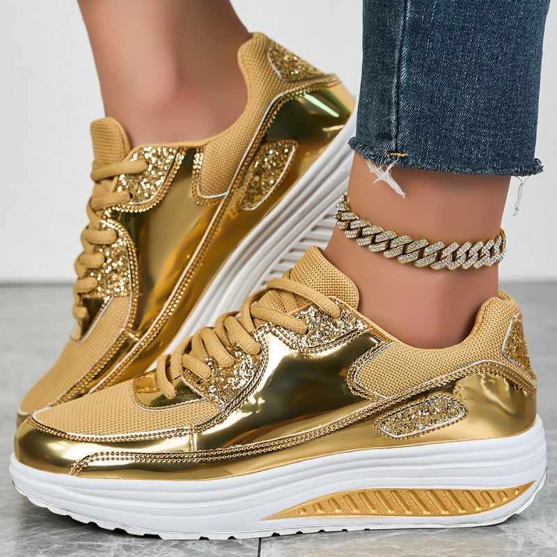 Goldene Sneaker mit Glitzerakzenten und weißer Sohle, getragen mit Jeans und einer silbernen Fußkette. Modische Damenschuhe, trendiger Look.