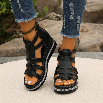 Schwarze Sandalen mit Riemchen und Keilabsatz, getragen mit zerrissenen Jeans. Modische Sommerschuhe für Damen, ideal für Freizeit und Outdoor.