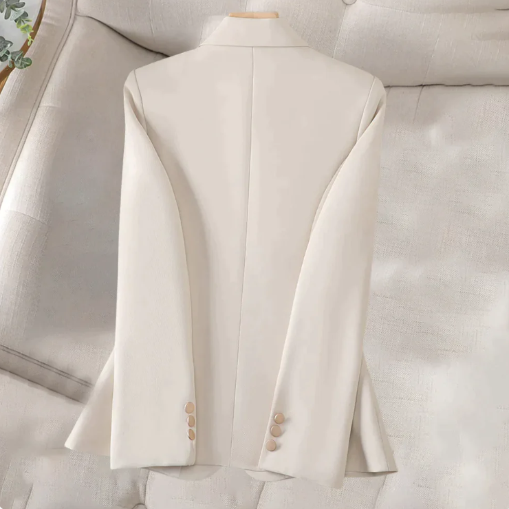 Beiger Damenblazer auf beigem Sofa, elegantes Design, lange Ärmel, Knöpfe an den Manschetten, stilvolle Damenmode, Business-Outfit.