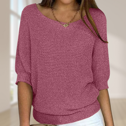 Frau trägt rosa Strickpullover mit Dreiviertelärmeln, kombiniert mit weißer Hose. Modetrend, Damenmode, lässiger Look, gemütlicher Stil.