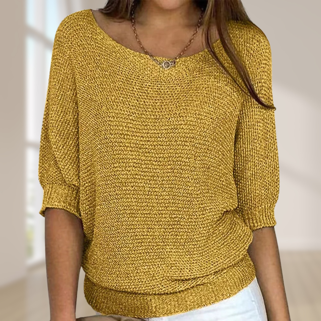 Frau trägt gelben Strickpullover mit Dreiviertelärmeln, kombiniert mit weißer Hose. Modetrend, Damenmode, gemütlicher Look, Herbstoutfit.