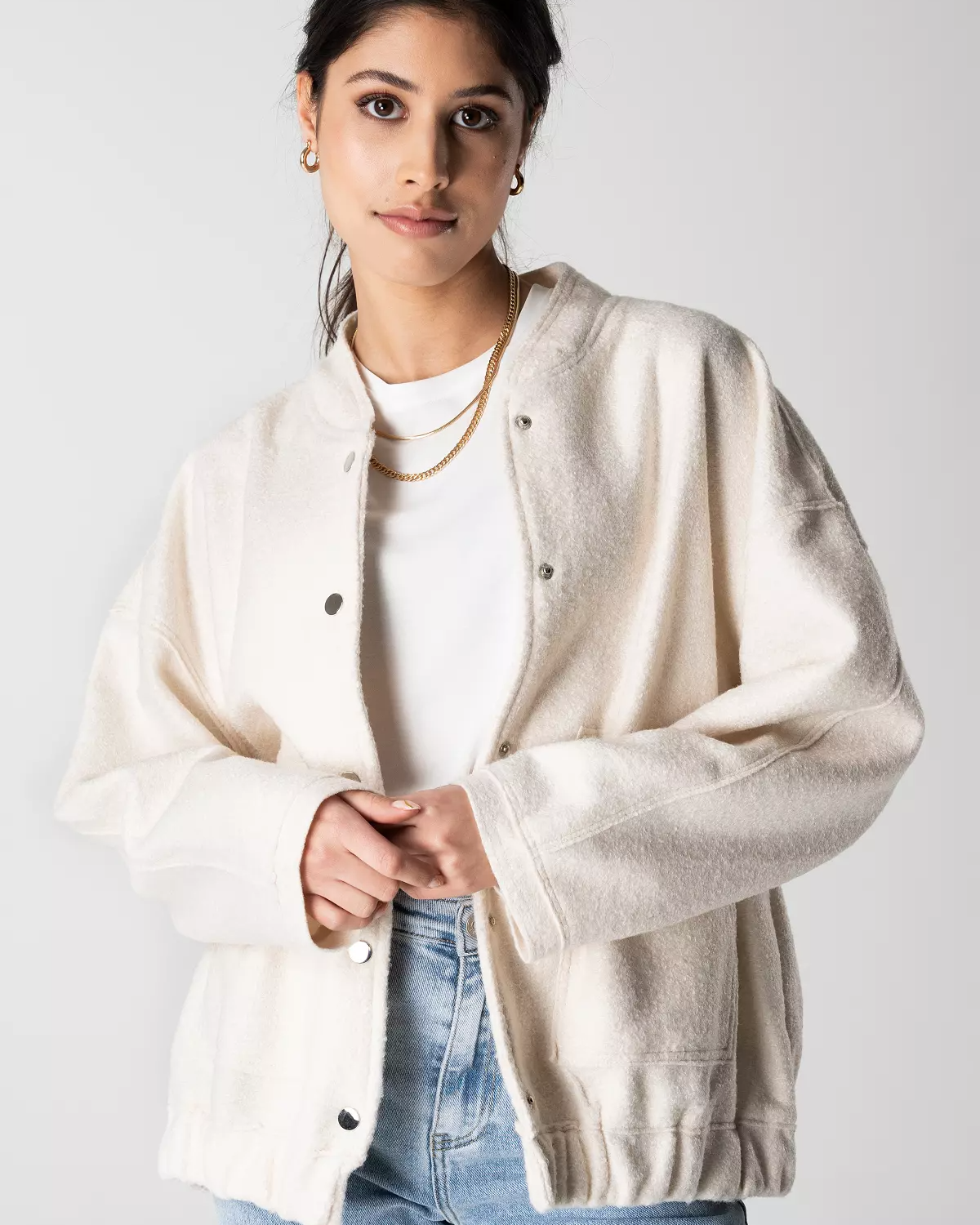 Frau trägt weiße Strickjacke, weißes T-Shirt und blaue Jeans. Modetrend, lässiger Stil, Damenmode, Herbstoutfit, Streetwear.