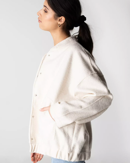 Frau in weißer, übergroßer Jacke mit Druckknöpfen, seitlich fotografiert. Modetrend, Damenbekleidung, lässiger Stil, Herbstmode.