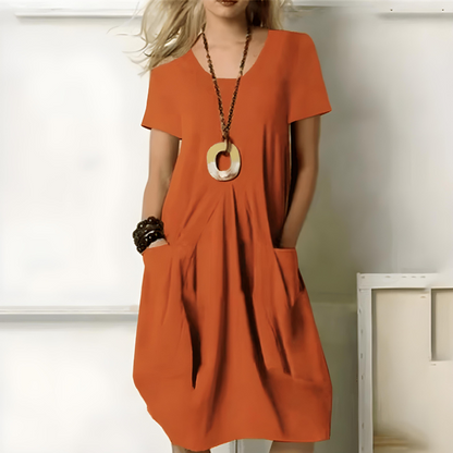 Frau in orangefarbenem Kleid mit Taschen, trägt große Halskette und Armbänder. Modetrend, Sommerkleid, Damenmode, lässiger Stil.