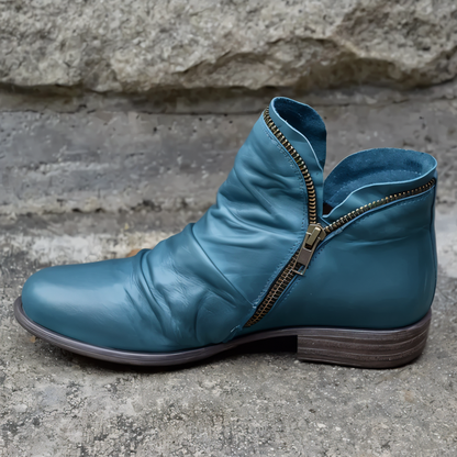 Blauer Lederstiefel mit seitlichem Reißverschluss, moderner Stil, auf Betonhintergrund. Hochwertige Damenmode, stilvolle Herbstschuhe.